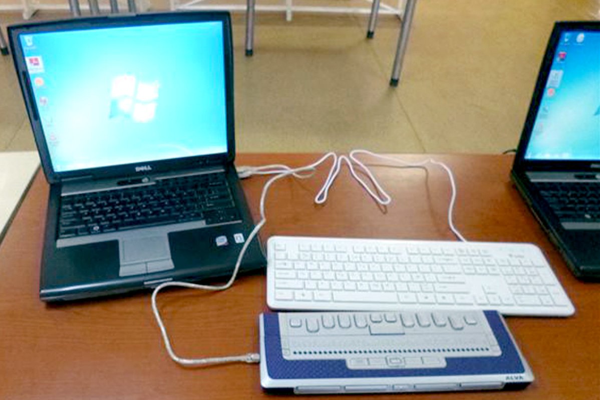 A Braille display and a keyboard are connected to a laptop.