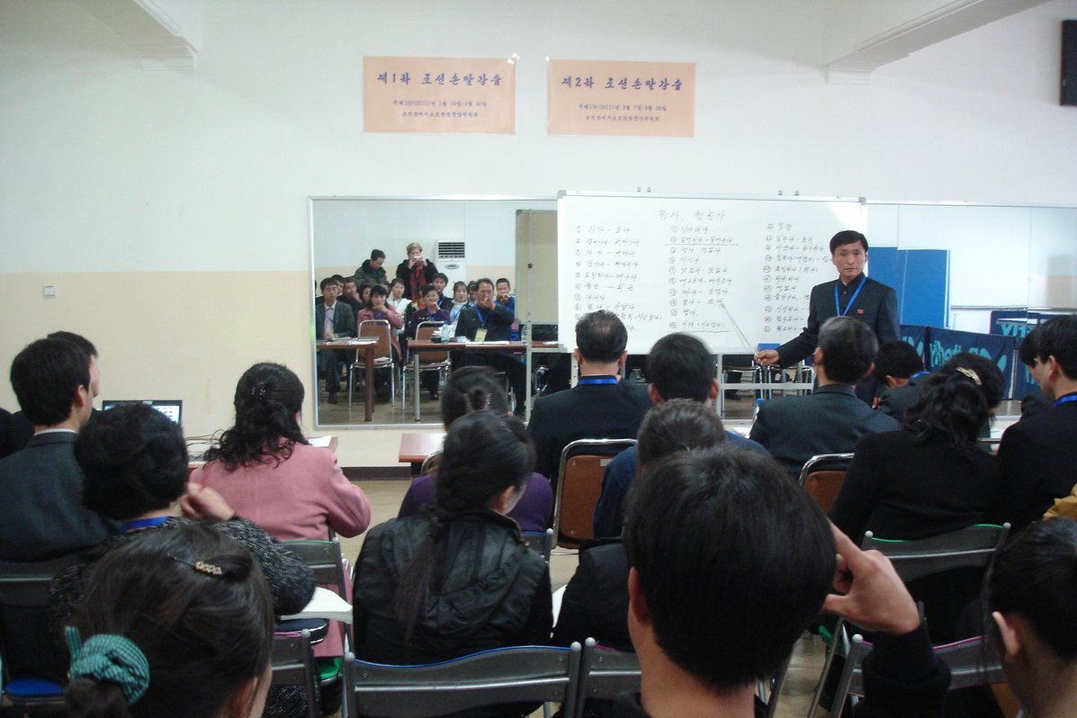 Many participants are in the course room. The teacher is standing in front of the board.